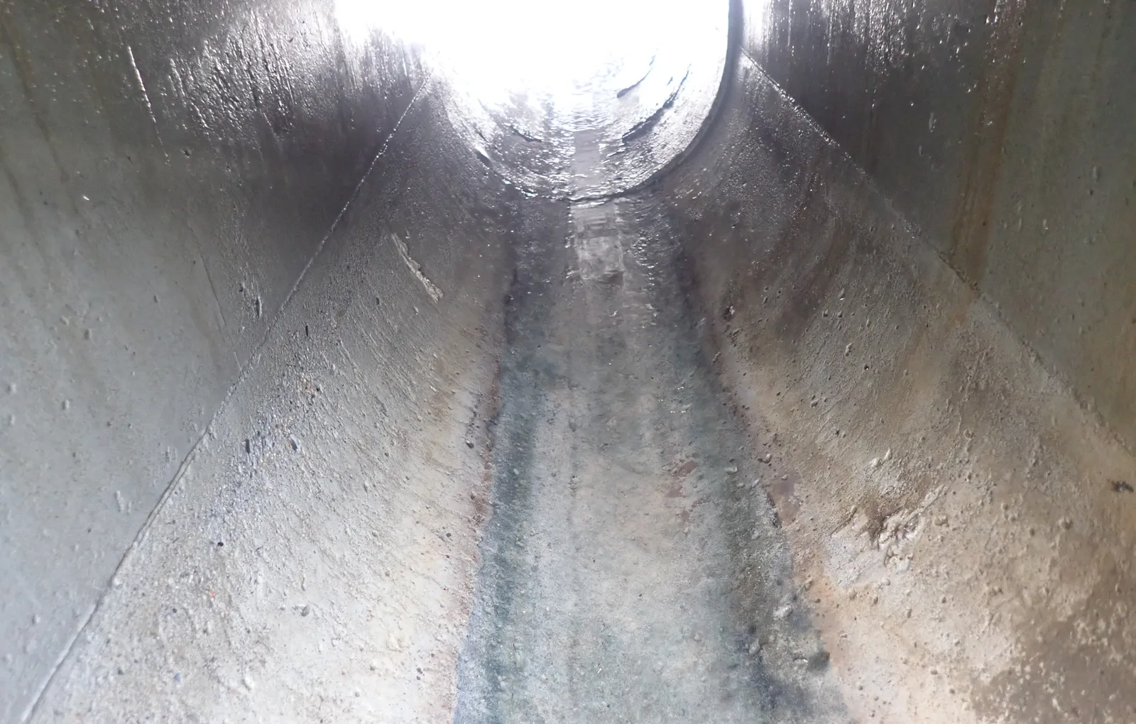 圓形管道內部，管底留著水流沖過的痕跡，管口透進亮光